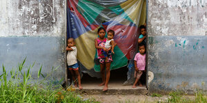 Fünf Kinder stehen am Eingang eines heruntergekommenen Gebäudes.