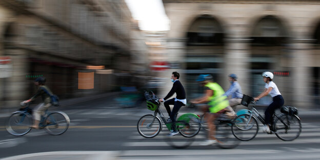 Menschen radeln auf dem Fahrrad vor unscharfer Stadtkulisse
