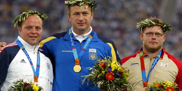 Die drei erstplatzierten des olympischen Kugelstrosswettbewerbs 2004 mit ihren Medaillen