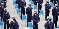Polizist:innen in Uniform in stehen vor ihren Stühlen