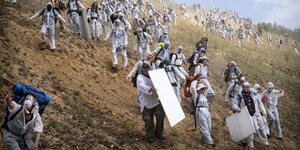 Aktivisten in hellen Schutzanzügen rennen in die Braunkohlegrube Garzweiler