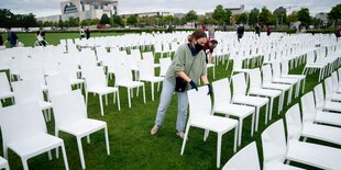 Ein Mensch stellt stühle vor dem Reichstag auf