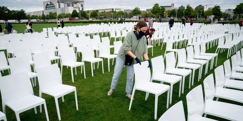 Ein Mensch stellt stühle vor dem Reichstag auf