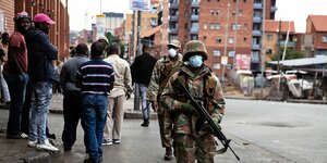 Soldaten mit Maschinengewehr gehen durch eine Straße in Johannesburg
