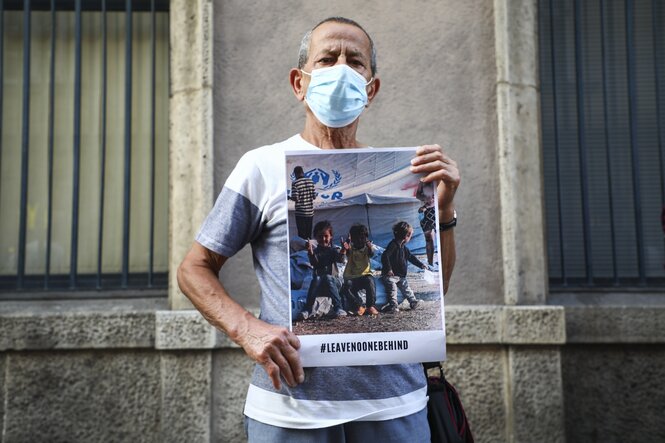 Demonstrantin mit Mundschutz und plakat