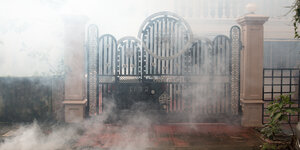 Nebelschwaden ziehen an einem Tor auf einer Straße vorbei