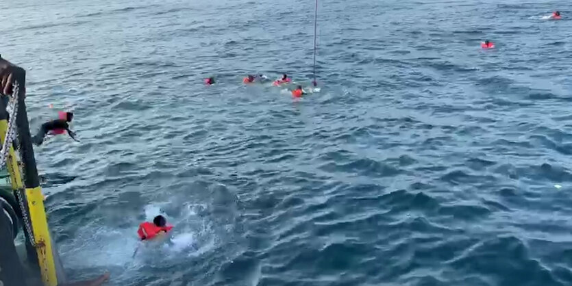 Geflüchtete springen von Bord der Open Arms um nach Palermo zu schwimmen