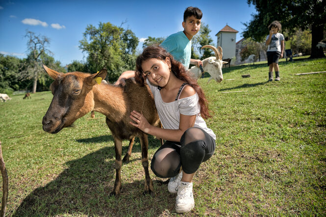 Ein Mädchen lässt sich mit einer braunhäutigen Ziege fotografieren