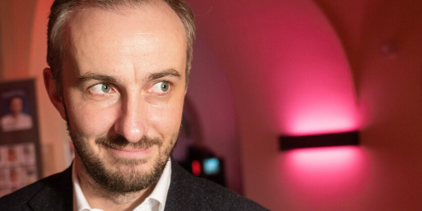 Jan Böhmermann, TV-Entertainer, vor rotem Hintergrund guckt nach rechts