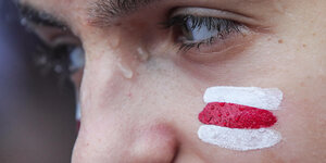 Das Gesicht eines Demonstranten mit den Farben von Belarus