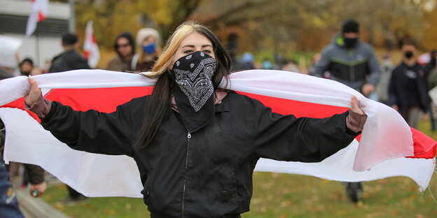 eine demonstrantin hält eine belarusisch e fahne hioch