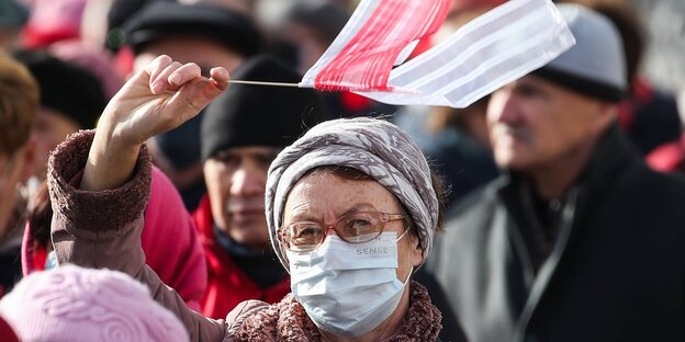 Eine Rentnerin mit rot-weißer Flagge in einer Menschenmenge