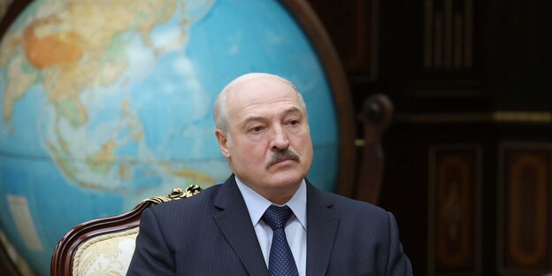 Der belarussische Präsident Alexander Lukaschenko sitzt vor einem roßen Globus