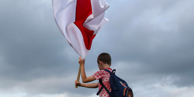 Ein Junge schwenkt eine rot-weiße Flagge.