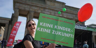 Eine Frau hält ein grünes Transparent auf dem "Keine Kinder, keine Zukunft" steht.