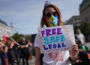Eine Frau fordert auf einem Transparent kostenlose, sichere und legale Abtreibungen.
