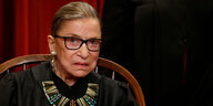 Ruth Bader Ginsburg sitzt mit ernstem Blick auf einem Stuhl