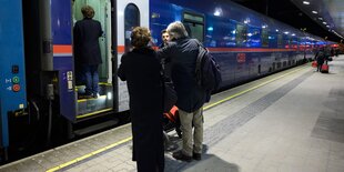 Menschen stehen auf einem nächtlichen Bahnsteig