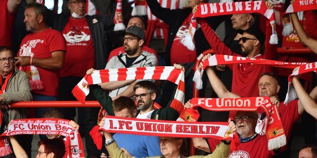 Fans mit rot-weißen Schals im Fußballstadion
