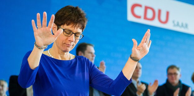 Annegret Kramp-Karrenbauer macht auf einem CDU-Parteitag eine beschwichtigende Handbewegung