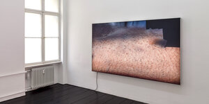 Ein Videoscreen von Seth Price an einer Wand in der Galerie Isabelle Bortolozzi