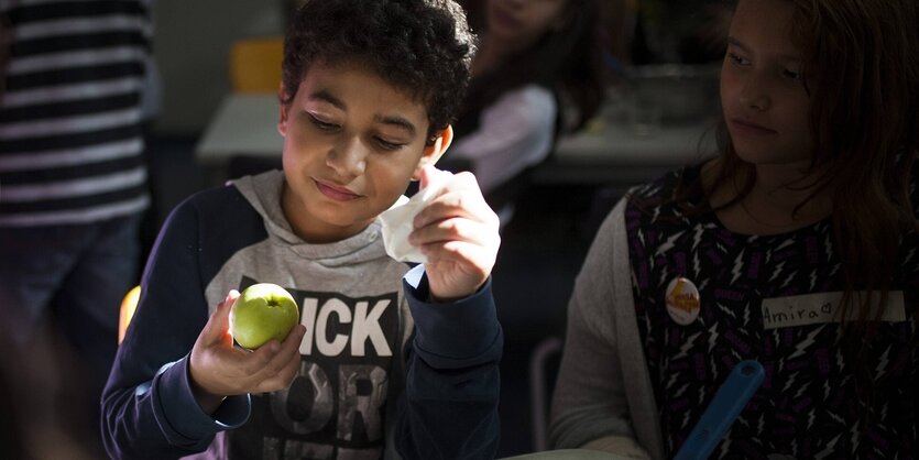 Ein Scvhüler hält eine Apfel