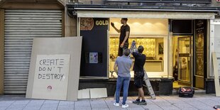 Drei Männer ersetzen eine zerborstene Schaufensterscheibe