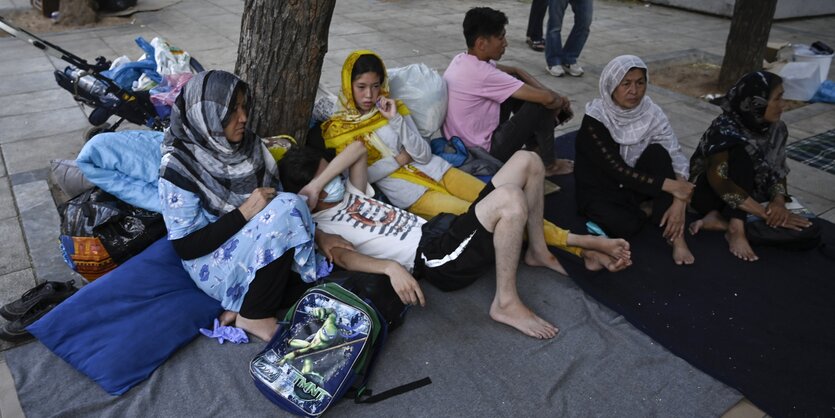 Eine Familie sitzt und liegt auf Decken auf dem Viktoria-Platz in Athen