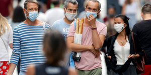 Menschen schlendern mit Maske durch Paris