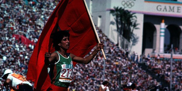 Läuferin mit marrokanischer Flagge in der Hand auf einer Ehrenrunde