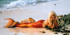 Eine Meerjungfrau aus dem Film "Splash" liegt an einem Strand und blickt in die Kamera