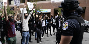 Demonstranten mit erhobenen Händen und Polizisten stehen sich gegenüber.