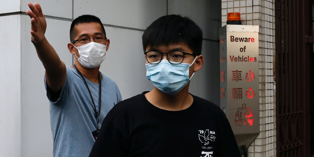 Joshua Wong trägt ein schwarzes T-Shirt und trägt einen Mundschutz