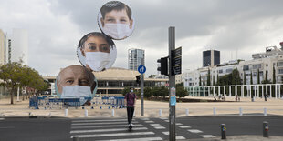 Ein Platz in Tel Aviv ist menschenleer, nur Werbebanner für einen Mundschutz ist zu sehen