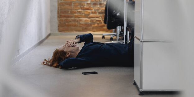 Eine Frau schäft unter ihrem Schreibtisch ein