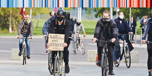 Aktivisten des Aktionsbündnisses Sand im Getriebe fahren mit Fahrrädern am Kanzleramt vorbei. «Andi B.Scheuert gehört gefeuert» steht auf dem Karton eines Radfahrers.