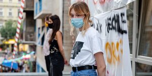Zwei junge Frauen bewachen den Eingang zur Universität und tragen Mund-Nasen-Schutz