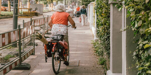 Eine Frau fährt auf einem Fahrrad auf dem Fußweg