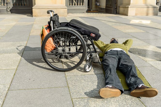 Menschen mit Assistenzbedarf legen sich auf den Platz vor dem Abgeordnetenhaus