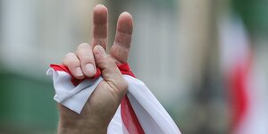 Eine Hand mit rot-weißer Flagge macht ein Victory-Zeichen.
