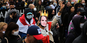 Eine Frau trägt bei einer Demonstration eine Gesichtsmaske von Sviatlana Tsikhanouskaya