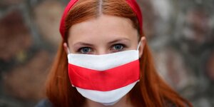 Portrait einer Frau, die eine weiß-rote Mundschutzmaske trägt