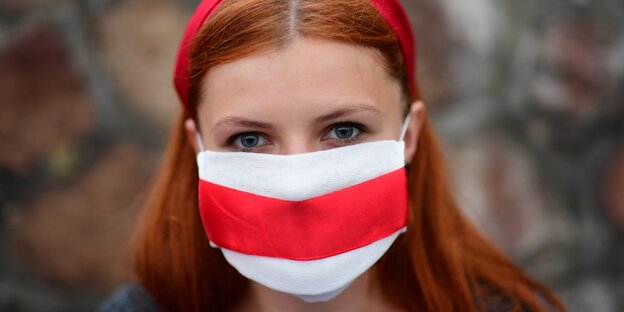 Potrait einer Frau, die eine rot-weiß gestreifte Mundschutzmaske trägt