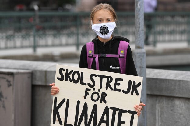 Greta Thunberg mit Maske und ihrem Schild für den Schulstreik fürs Klima