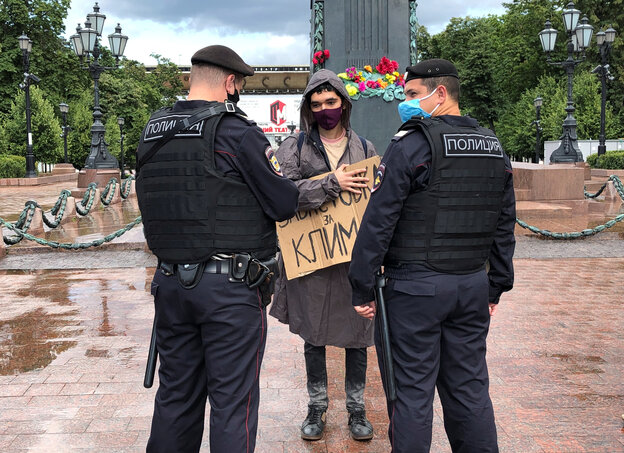 Altivistin mit Schild wird in Moskau von zwei Polizisten befragt