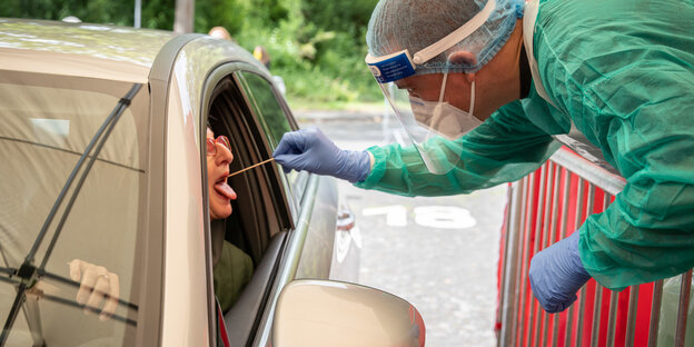 Ein Mann nimmt einen Corona-Test bei einer Frau im Auto