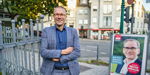 OB-Kandidat Uwe Schneidewind vor einem Plakat.