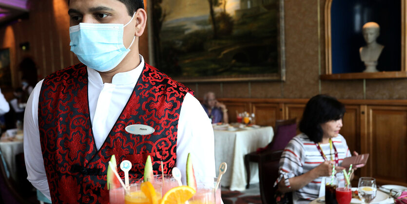 Ein Mitarbeiter trägt in der Kantine eines Kreuzfahrtschiffs eine Gesichtsmaske