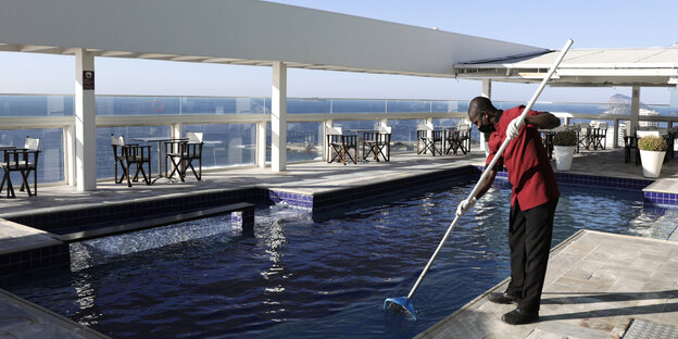 Ein Arbeiter reinigt den Pool eines Hotels