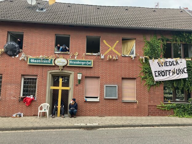 Hausfront mit Transparent "Wiedereröffnung" und einer Person davor Hausfront mit Transparent "Wiedereröffnung" und einer Person davor